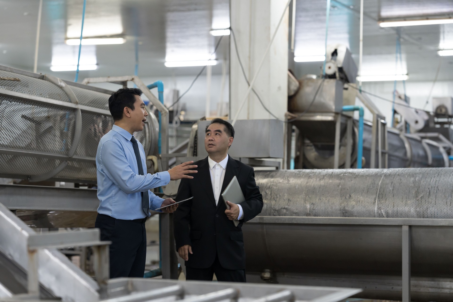 Canned fish factory, seafood manufacturing and processing. Manager team discussion and inspecting of pile of frozen fresh sea fish on ice at workplace of workers area. Seafood processing conveyor belt