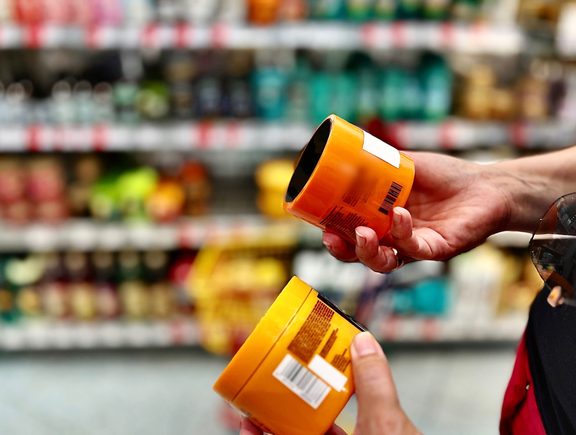 A woman holds jars of cream in her hands, chooses face and body care products in the supermarket in the summer